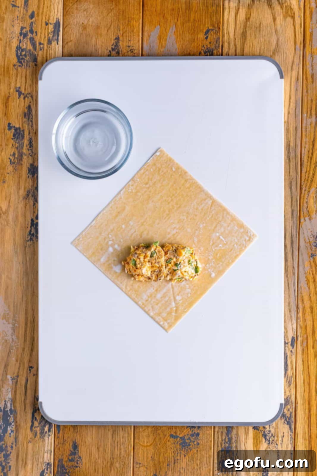 Spicy Creamy Egg Roll Poppers 7 An egg roll wrapper with a generous amount of jalapeño popper filling carefully placed on its bottom third.