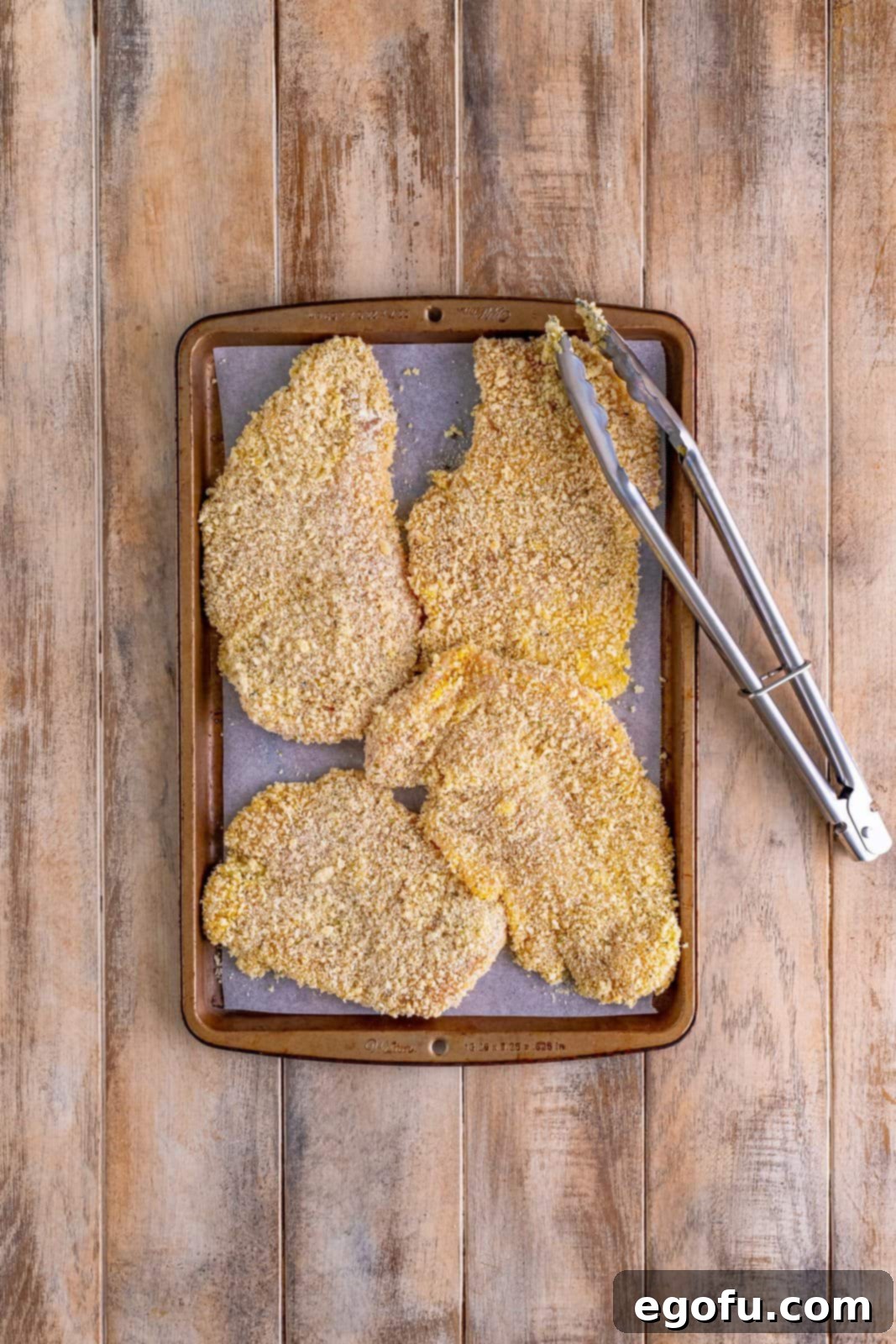 A baking sheet full of breaded chicken.