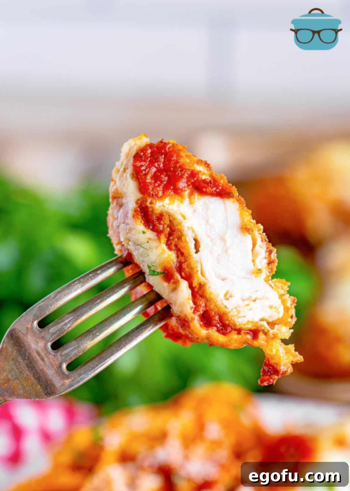 A fork holding a bite of homemade chicken parmesan.