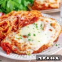 A plate of chicken parmesan and spaghetti with tomato sauce.