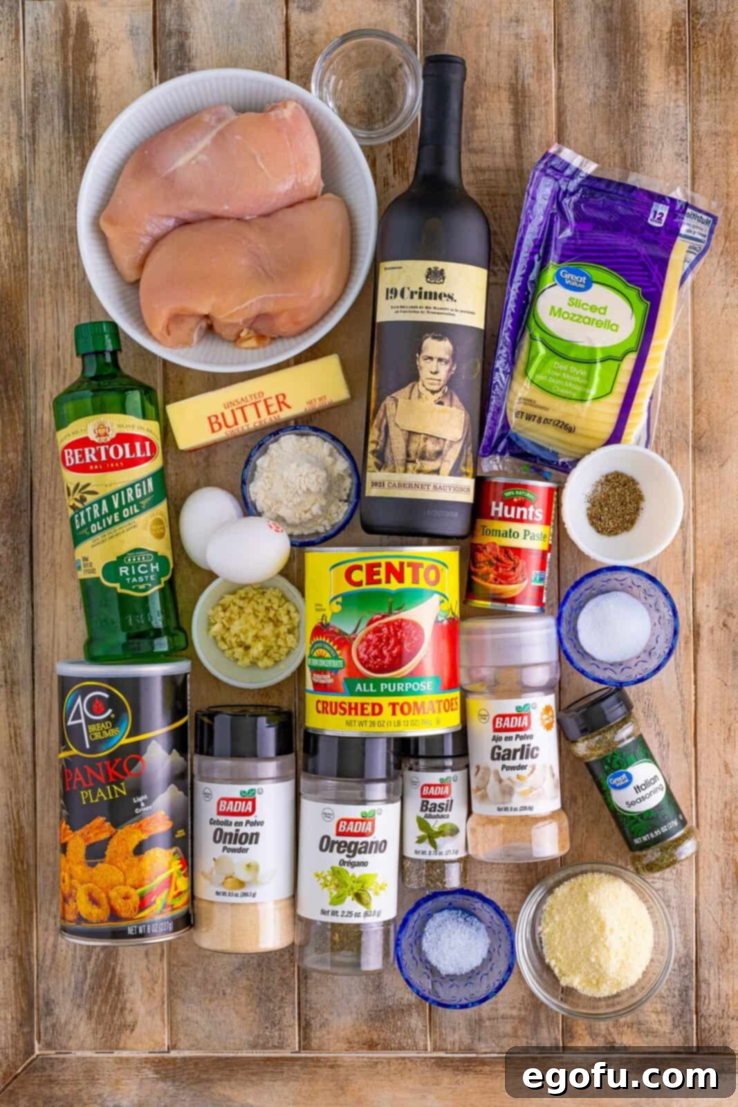 Olive oil, garlic cloves, tomato paste, dried oregano, dried basil, onion powder, garlic powder, kosher salt, black pepper, dry red wine, crushed tomatoes, grated parmesan cheese, granulated sugar, unsalted butter, chicken breasts, all-purpose flour, large eggs, water, panko breadcrumbs, grated parmesan cheese, Italian seasoning, and mozzarella cheese.