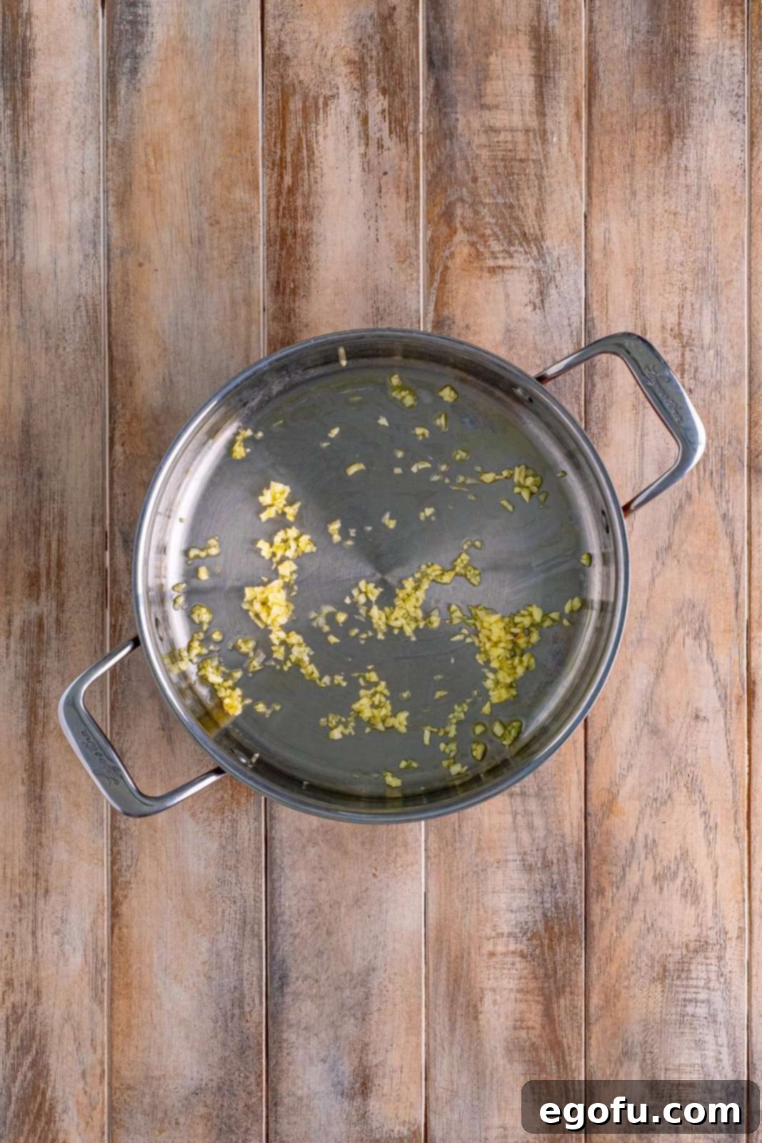 A skillet with garlic and olive oil.