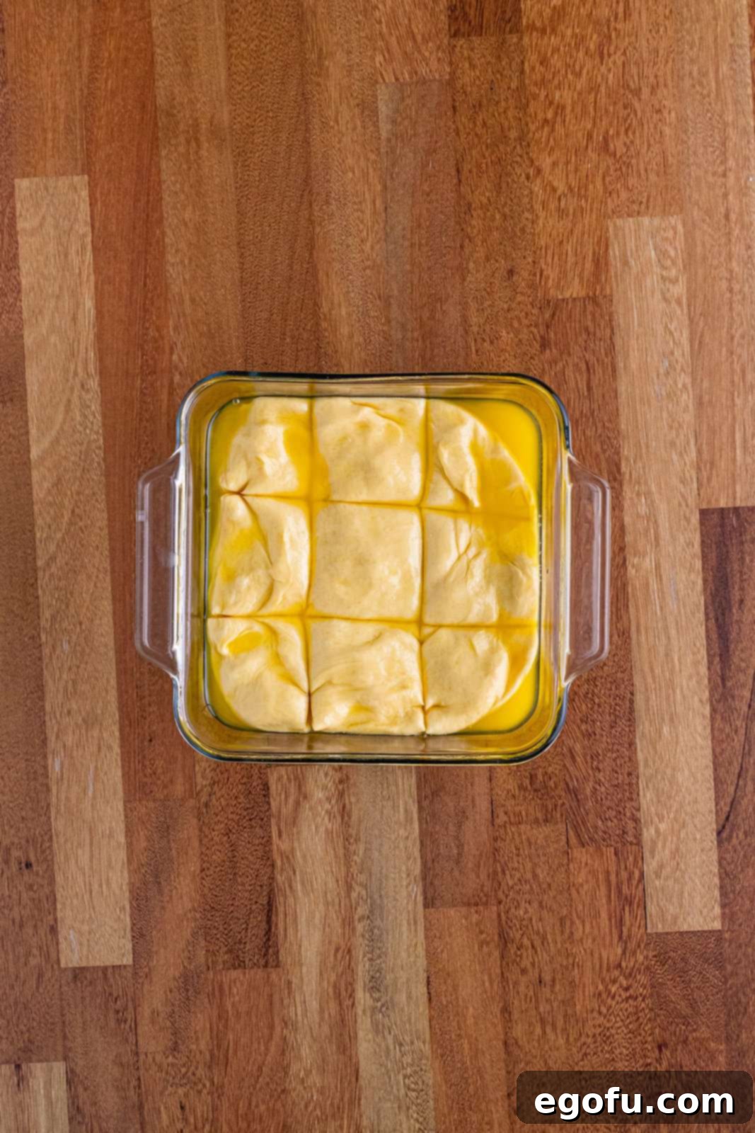 Butter Bathed Cloud Rolls 13 A glass baking dish with bread dough neatly cut into nine individual rolls, ready for a second rise.