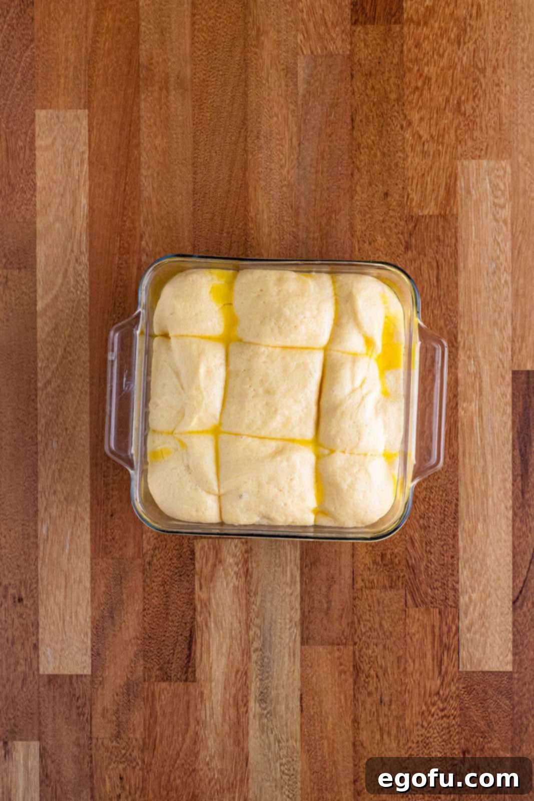 Butter Bathed Cloud Rolls 14 A glass baking dish filled with bread roll dough that has beautifully doubled in size during its second rise, filling the pan.