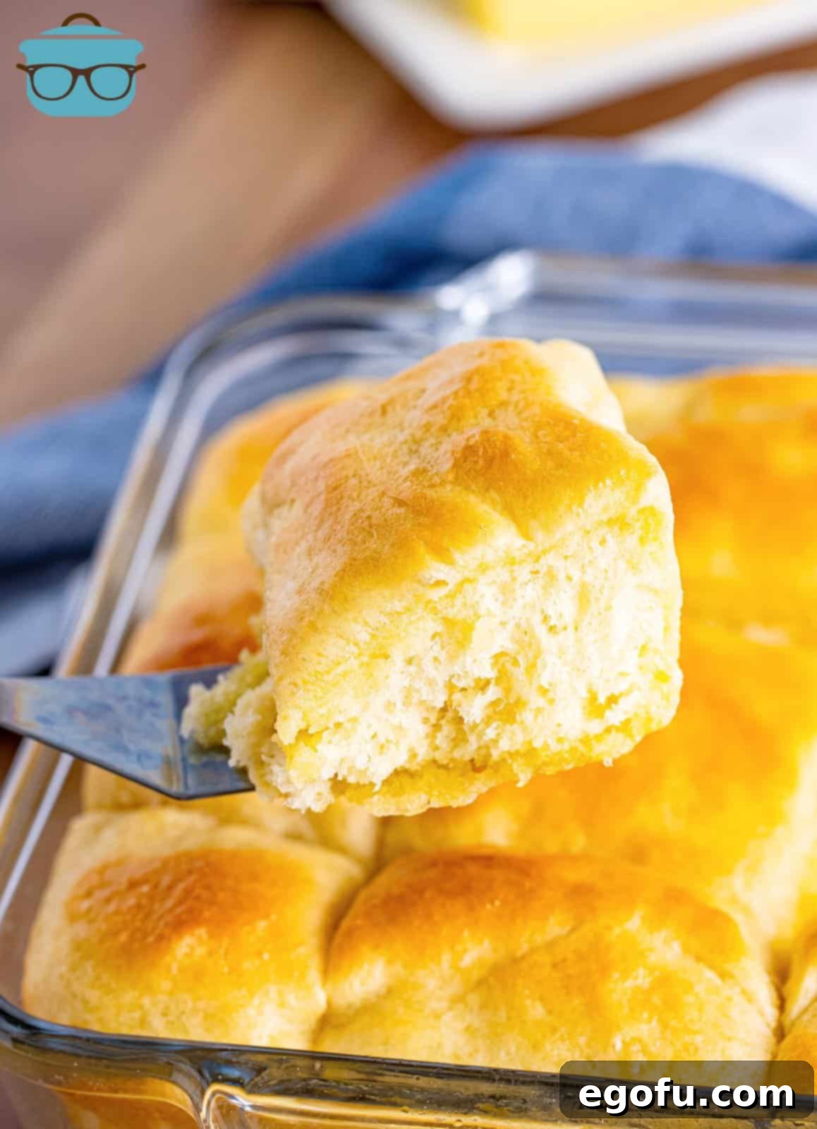 Butter Bathed Cloud Rolls 16 A serving spatula delicately lifting a warm, golden-brown yeast roll from the baking dish, ready for plating.