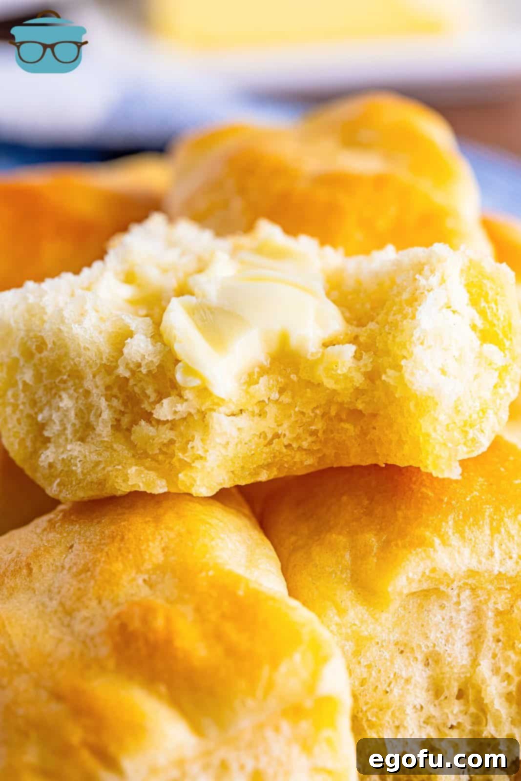 Butter Bathed Cloud Rolls 17 A close-up shot of several butter swim yeast rolls piled together, with one roll enticingly torn open to reveal its fluffy interior.