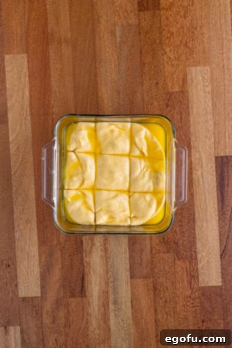 Butter Bathed Cloud Rolls 26 A glass dish with bread dough cut into nine rolls.