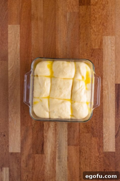 Butter Bathed Cloud Rolls 27 A glass dish with bread roll dough that just doubled in size.