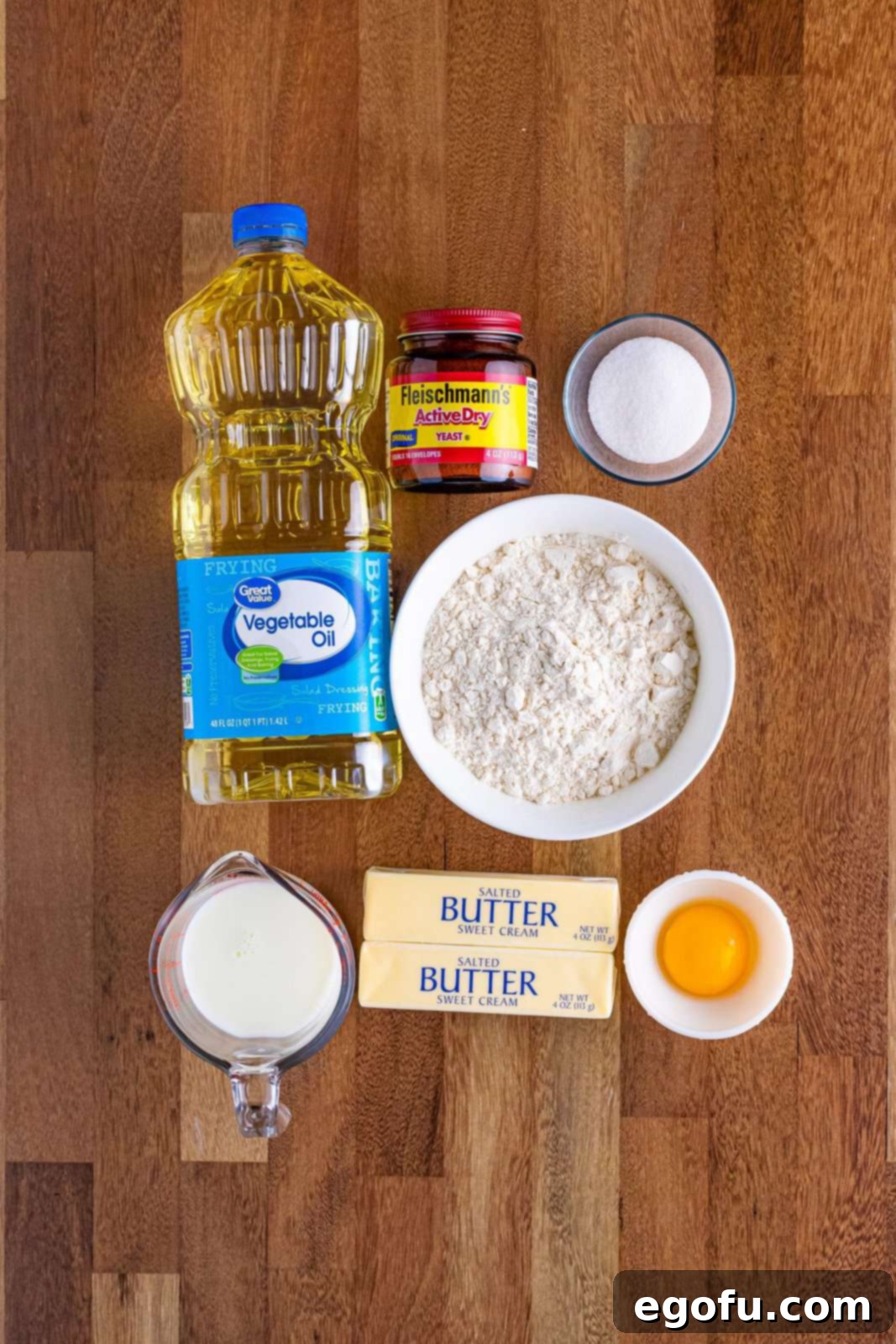 Butter Bathed Cloud Rolls 4 A beautifully arranged display of all the essential ingredients for butter swim yeast rolls: salted butter, granulated sugar, milk, active dry yeast, egg yolk, all-purpose flour, and vegetable oil.