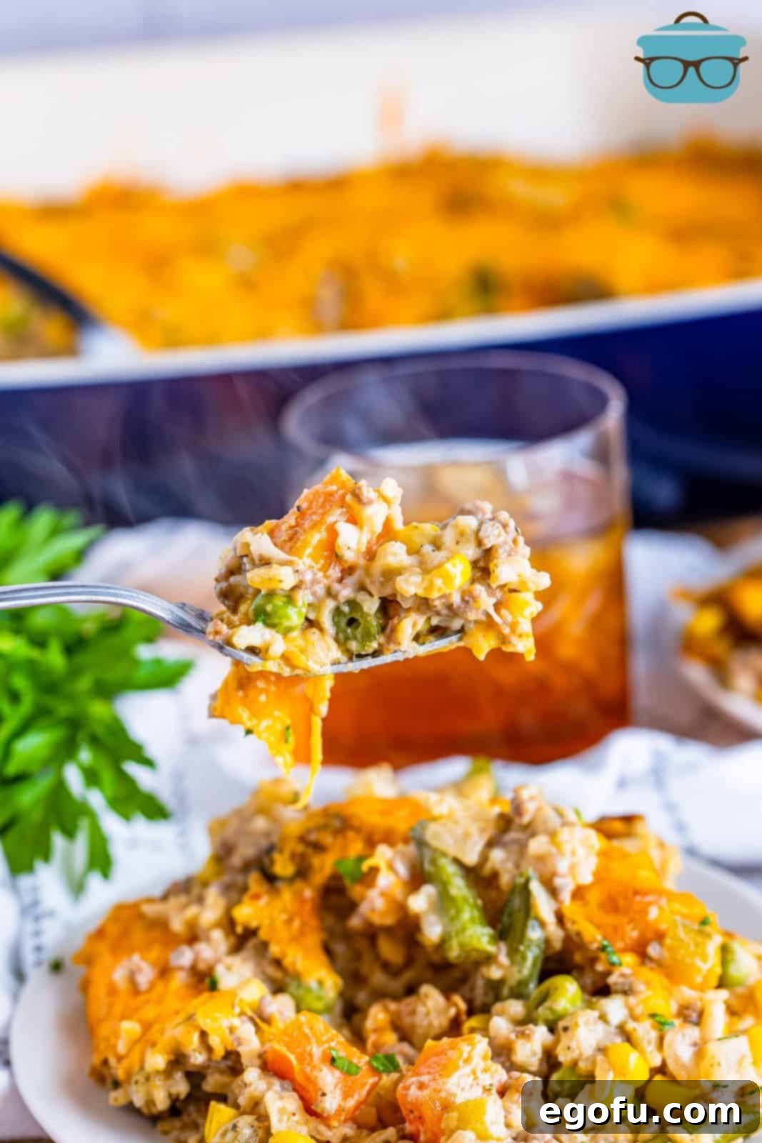 Golden Cheesy Beef and Rice Bake 11 A fork holding a bite of the cheesy ground beef and rice casserole, showcasing the melted cheese and hearty ingredients.