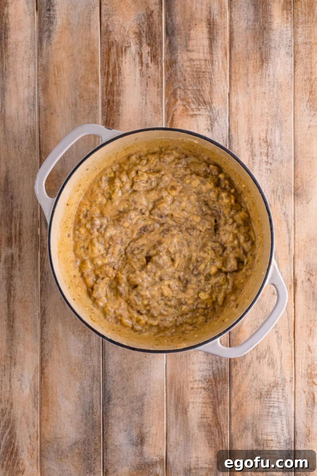 Golden Cheesy Beef and Rice Bake 6 A dutch oven containing cooked ground beef, onions, garlic, cream of celery soup, beef stock, and a blend of spices, all mixed together.