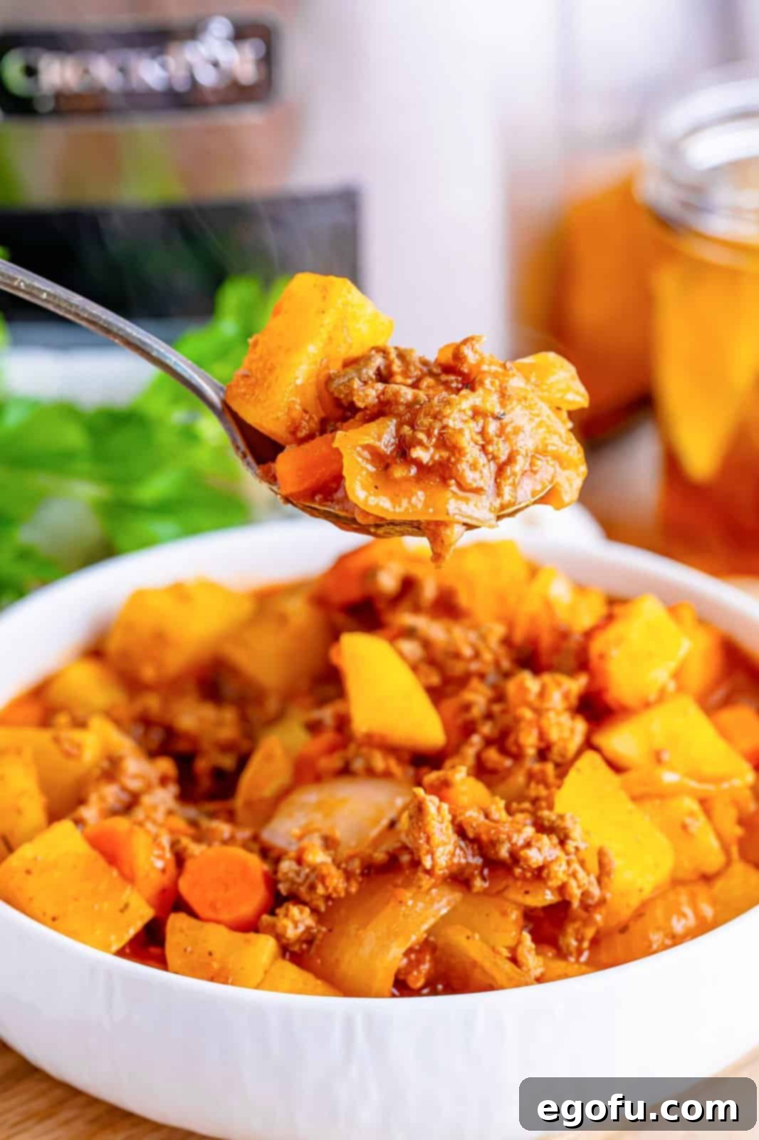 Slow Cooker Humble Stew 2 A bowl of Slow Cooker Poor Man's Stew with a spoon holding a bite above it, showcasing its rich texture and ingredients.