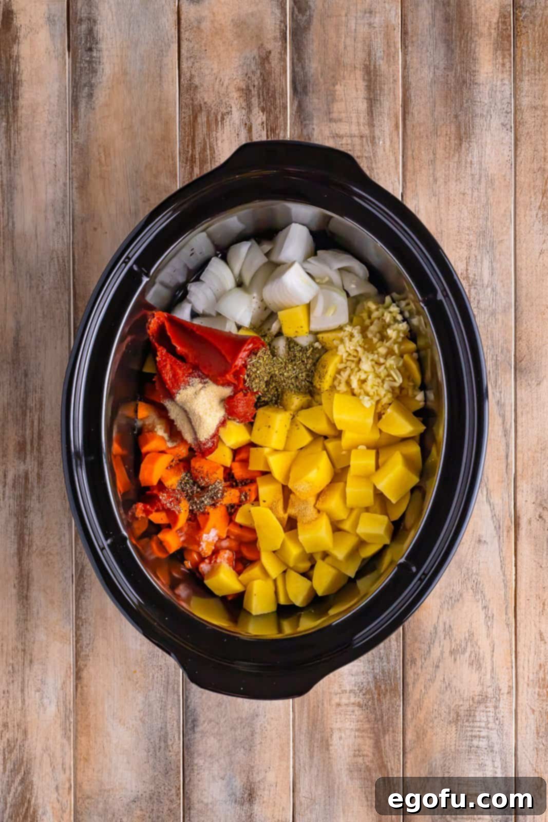 Slow Cooker Humble Stew 6 Slow Cooker insert with ground beef, potatoes, carrot, onion, garlic, water, tomato paste, Italian seasoning, salt, garlic powder, onion powder, and black pepper, all combined and ready to cook.