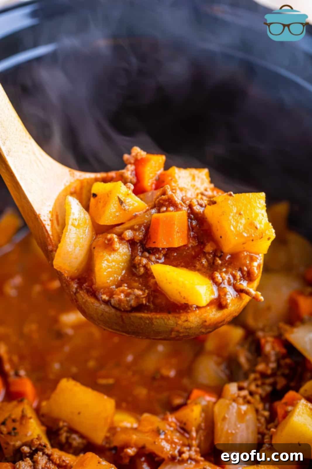 Slow Cooker Humble Stew 8 A Crockpot of Poor Man's Stew with a wooden spoon holding some of it up close to see the ingredients and rich broth.