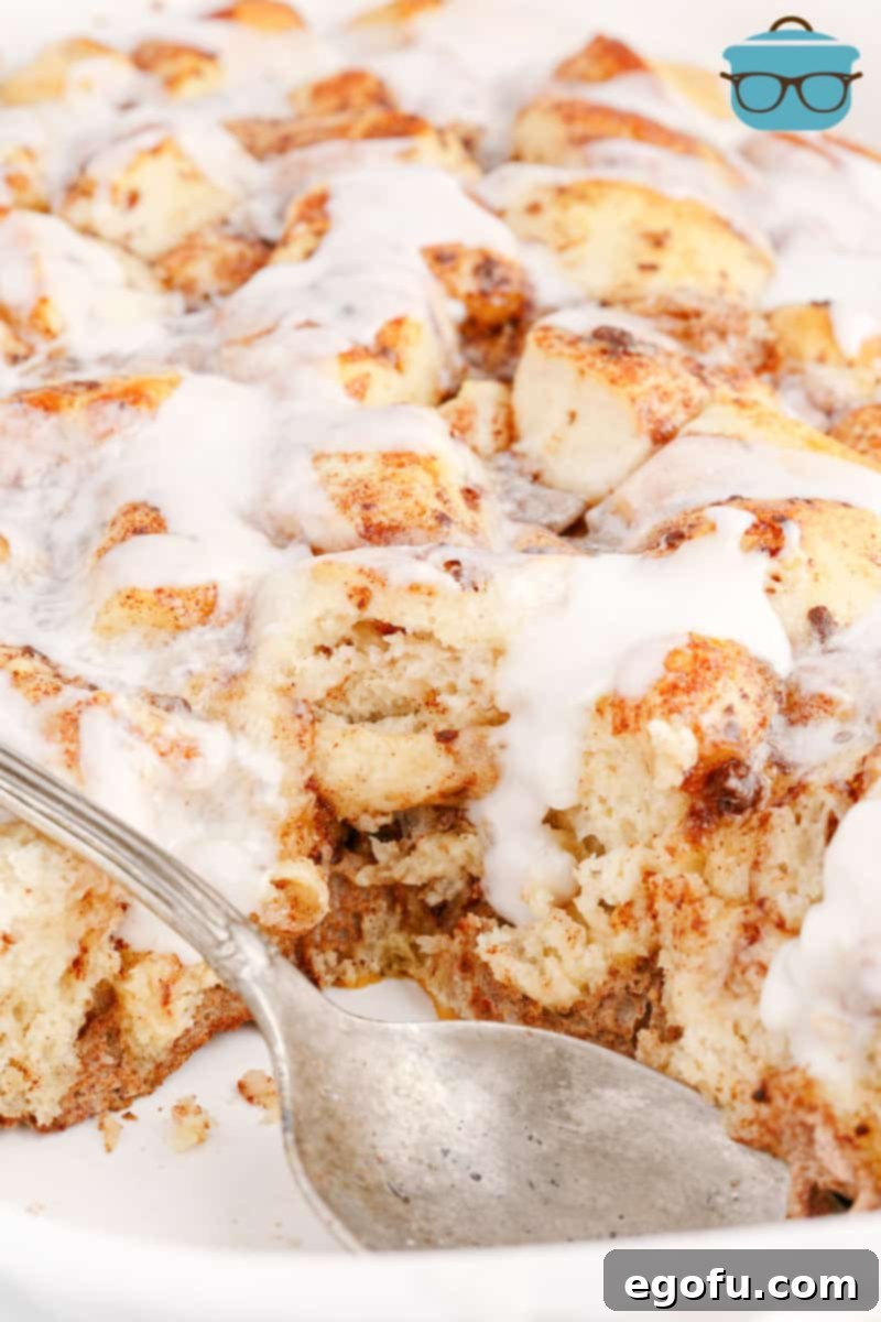 Pull-Apart Cinnamon Delight 2 A utensil holding a bite of a Cinnamon Roll Casserole, showcasing its gooey texture and golden brown crust.