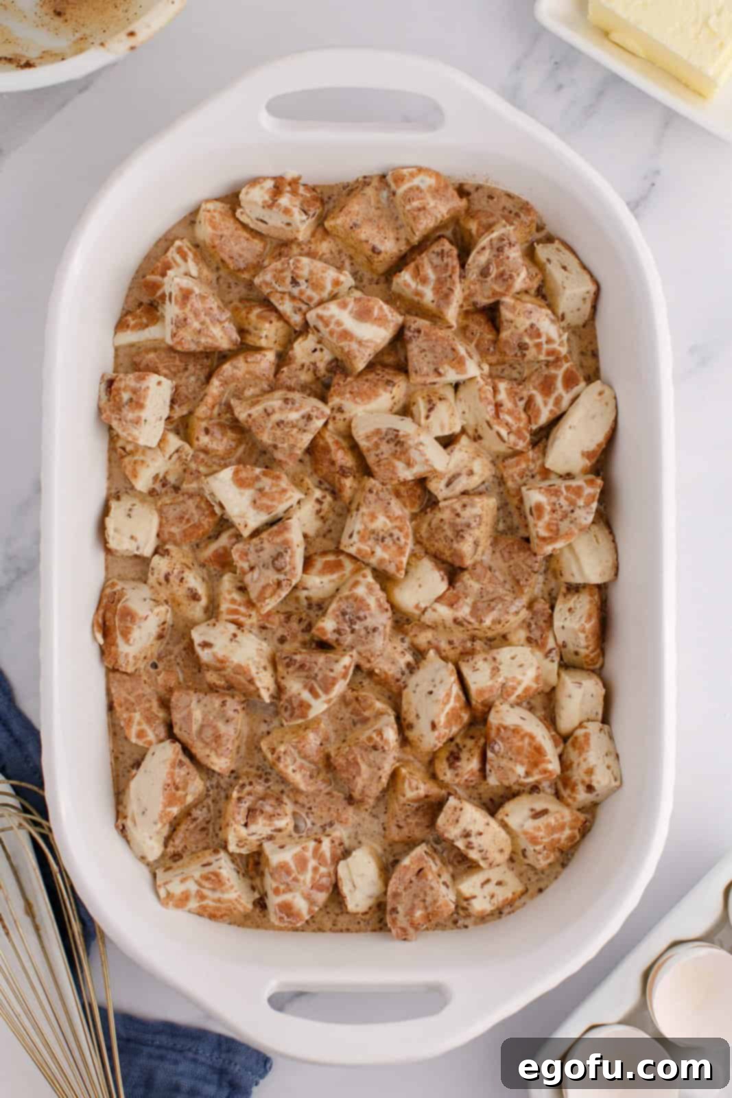 Pull-Apart Cinnamon Delight 6 An uncooked Cinnamon Roll Casserole in a baking dish, with the custard mixture poured over the rolls, ready for the next step.