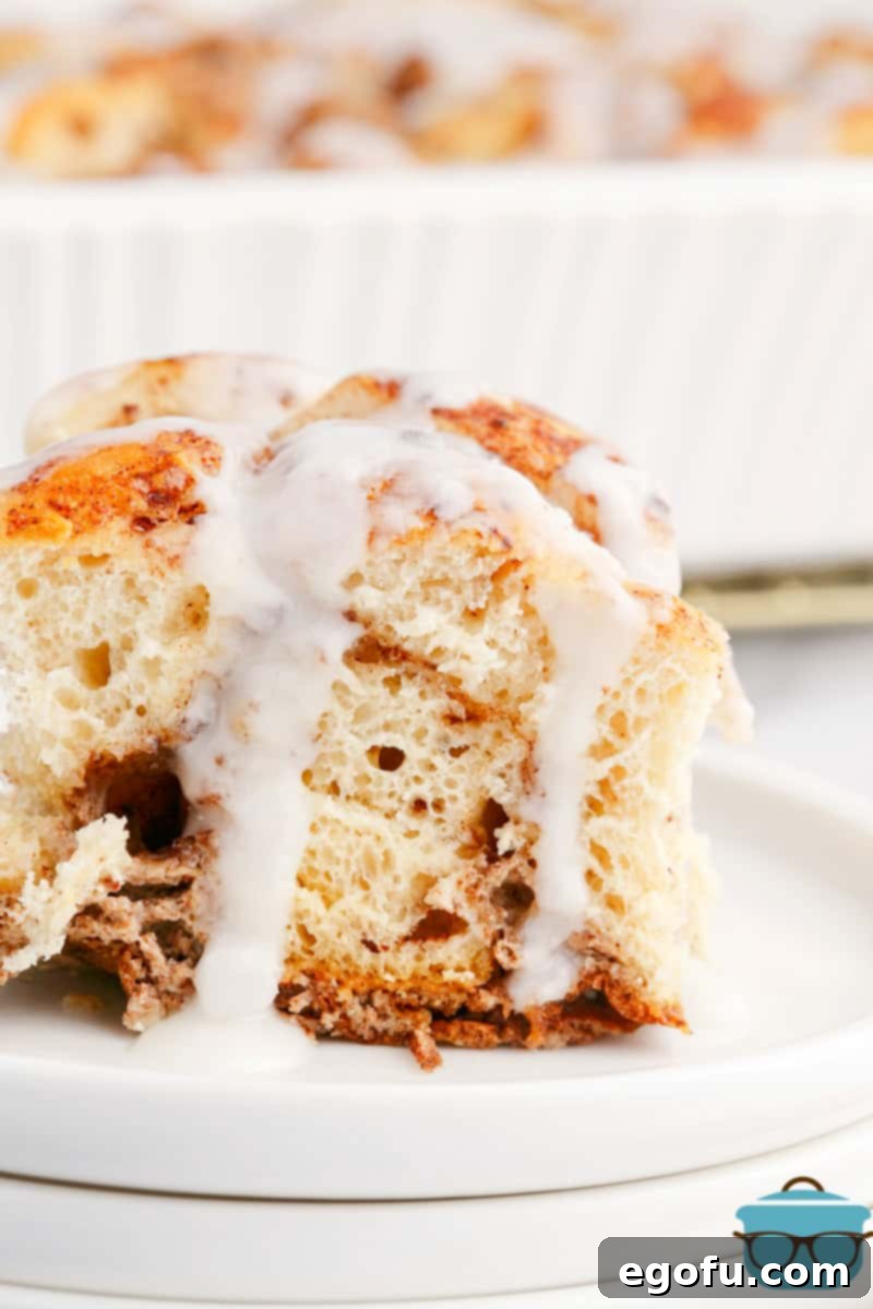 Pull-Apart Cinnamon Delight 9 A plate holding a serving of Cinnamon Bun Casserole, with the sweet icing gracefully dripping down, inviting a delicious bite.