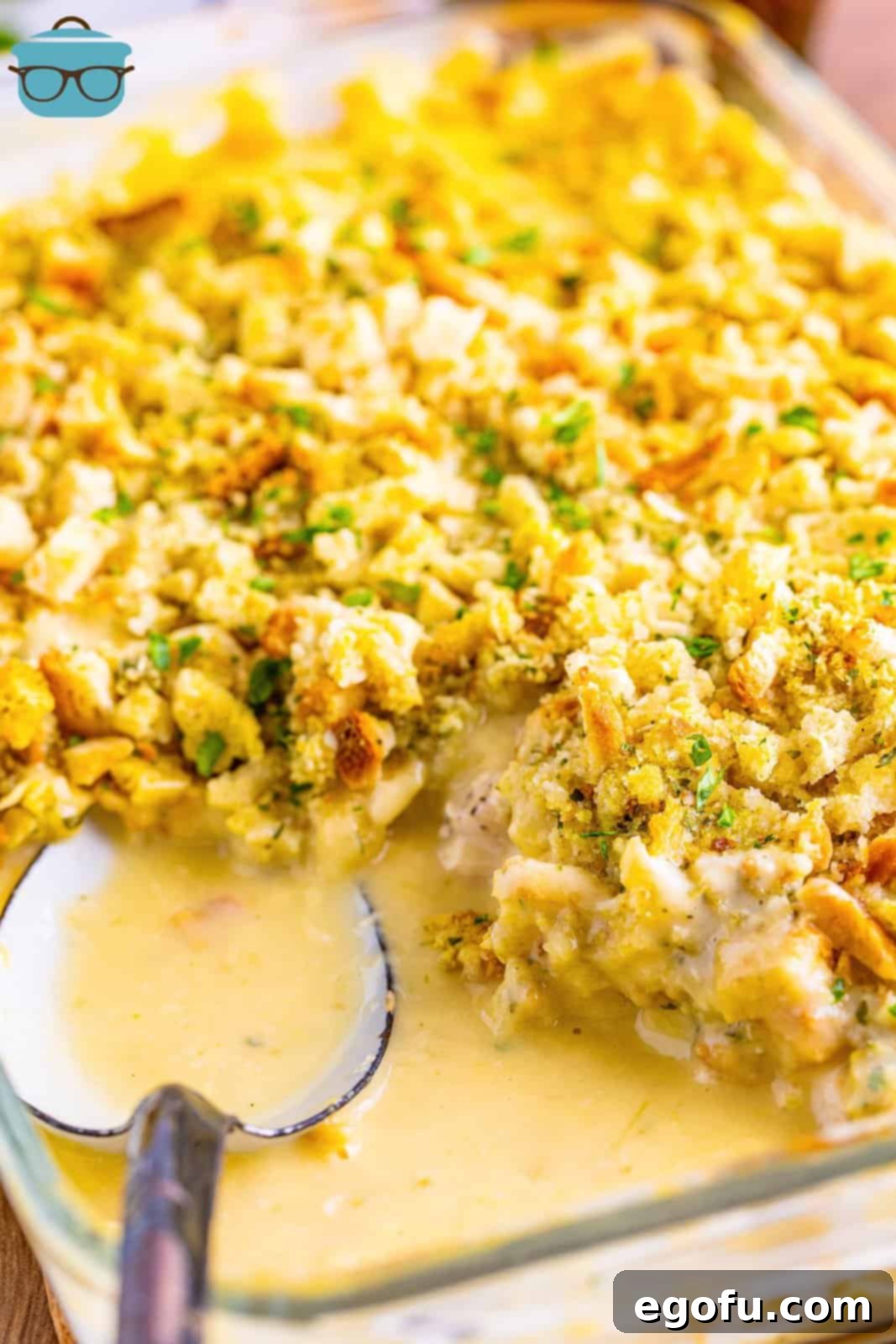 A casserole dish with a Chicken and Stuffing Casserole with a serving spoon and a serving removed.