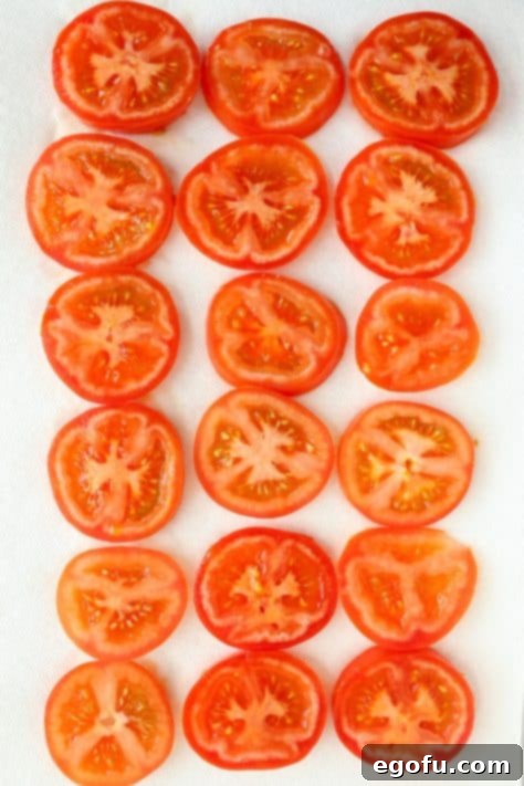 Sliced up tomatoes sitting, draining on some paper towels.