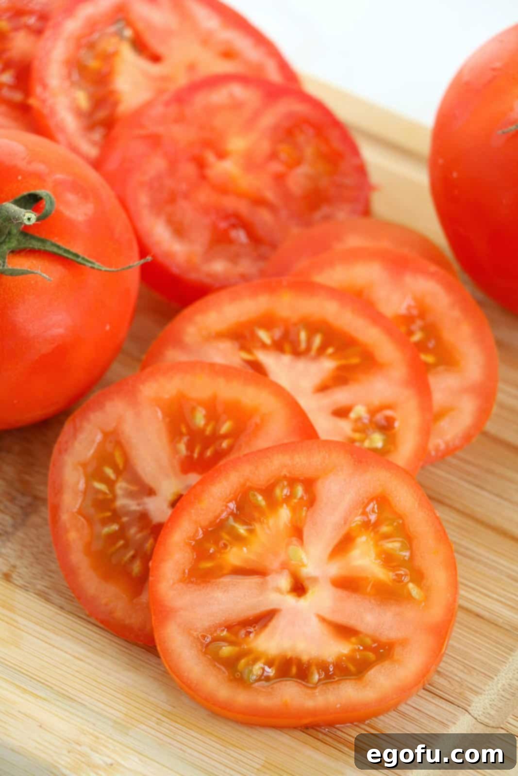 Some sliced beefsteak tomatoes on a cutting board.