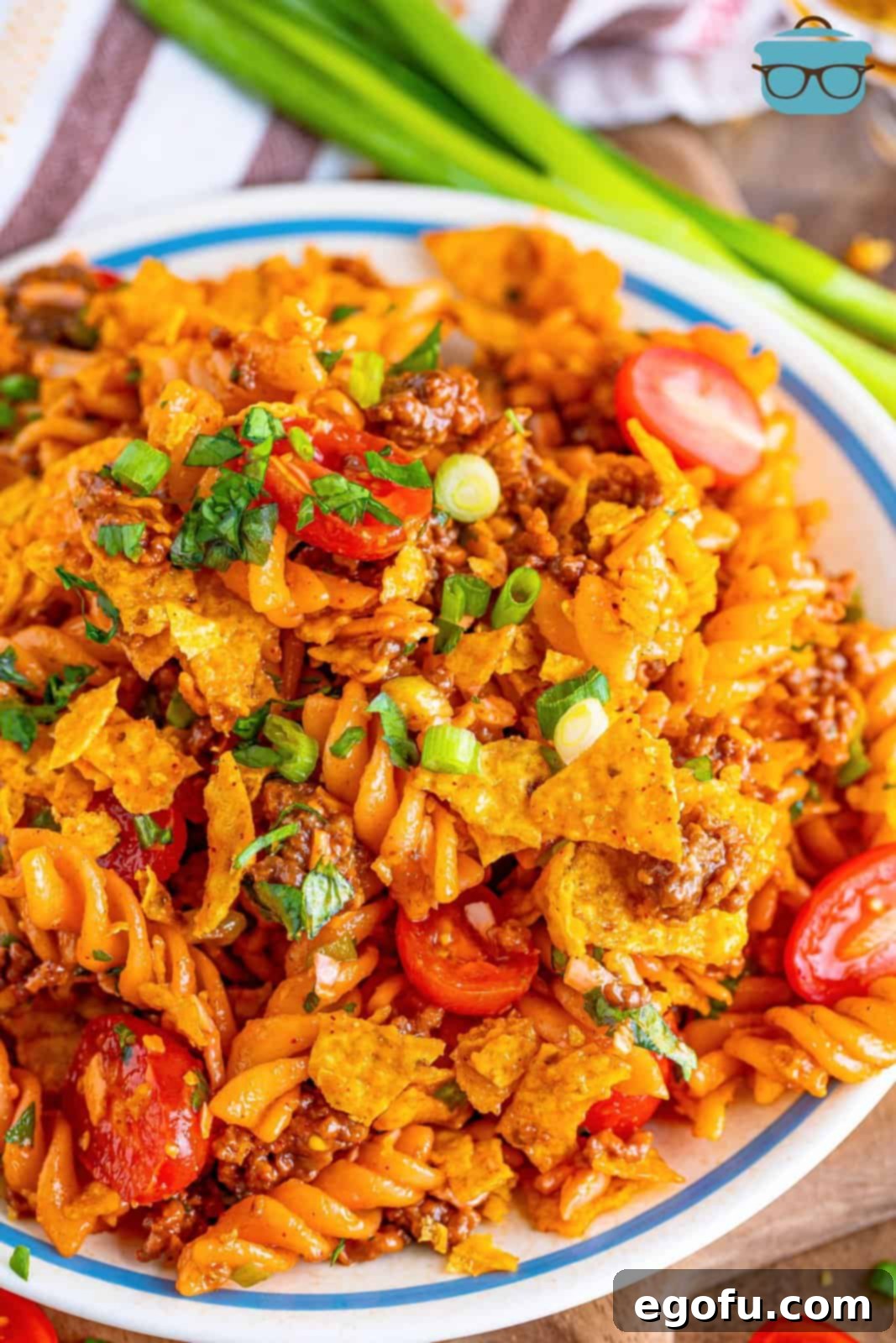 Looking down on a plate of pasta salad with taco seasoning, adorned with crushed Doritos and fresh cilantro.