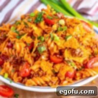 A plate of taco pasta salad with doritos crumbled on top.