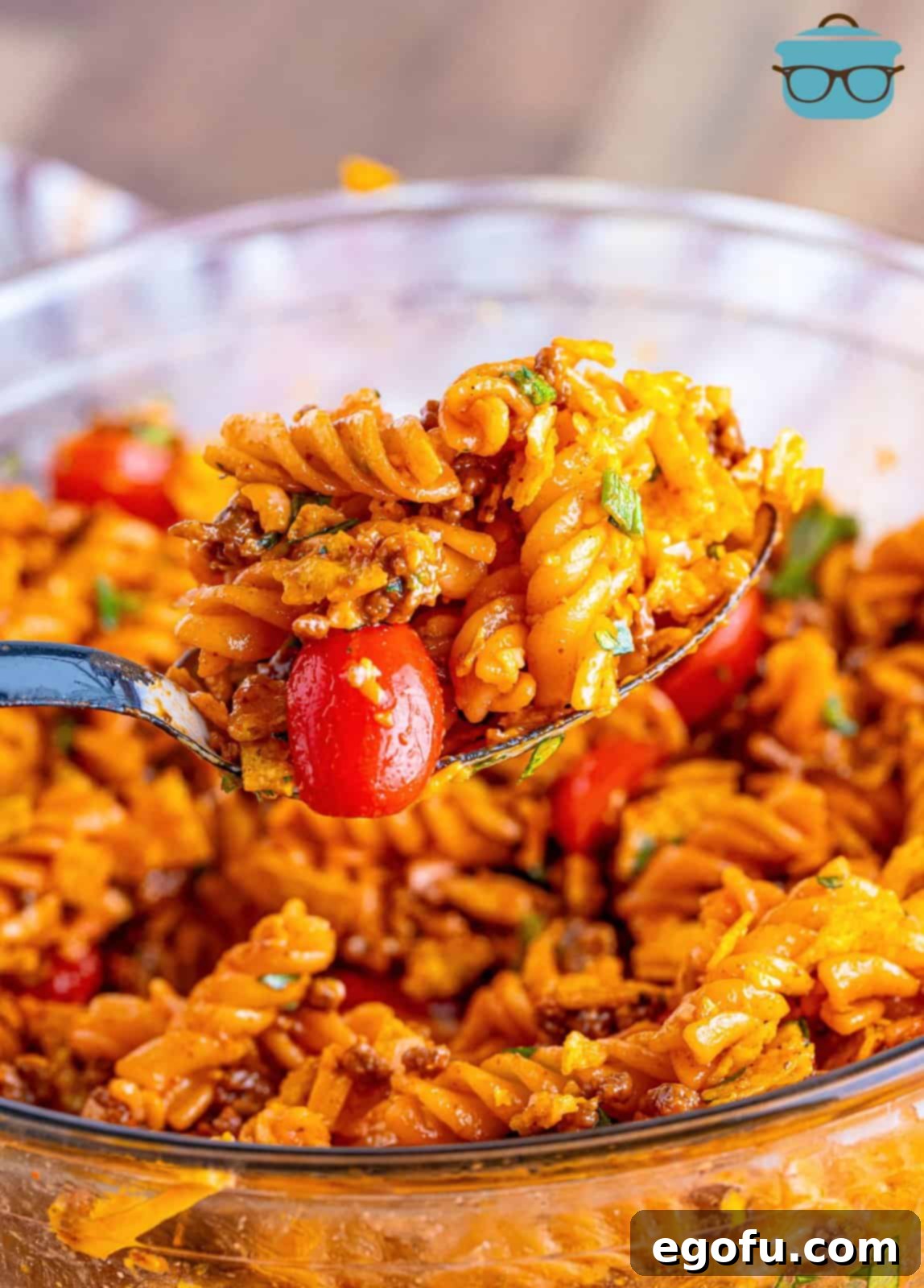 A beautifully presented bowl of taco pasta salad with fresh tomatoes and herbs on top.