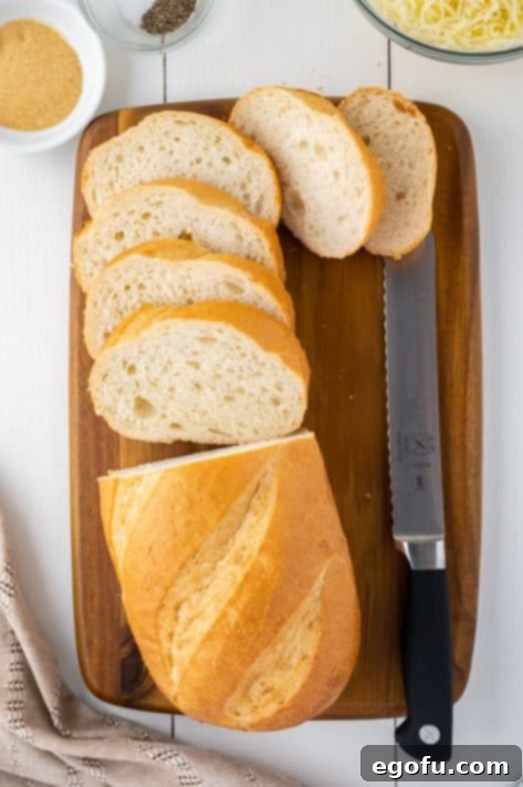 A cutting board with a half sliced loaf of bread and a bread knife.