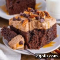 A plate holding a fork with a bite of poke cake and a slice of turtle poke cake next to it.