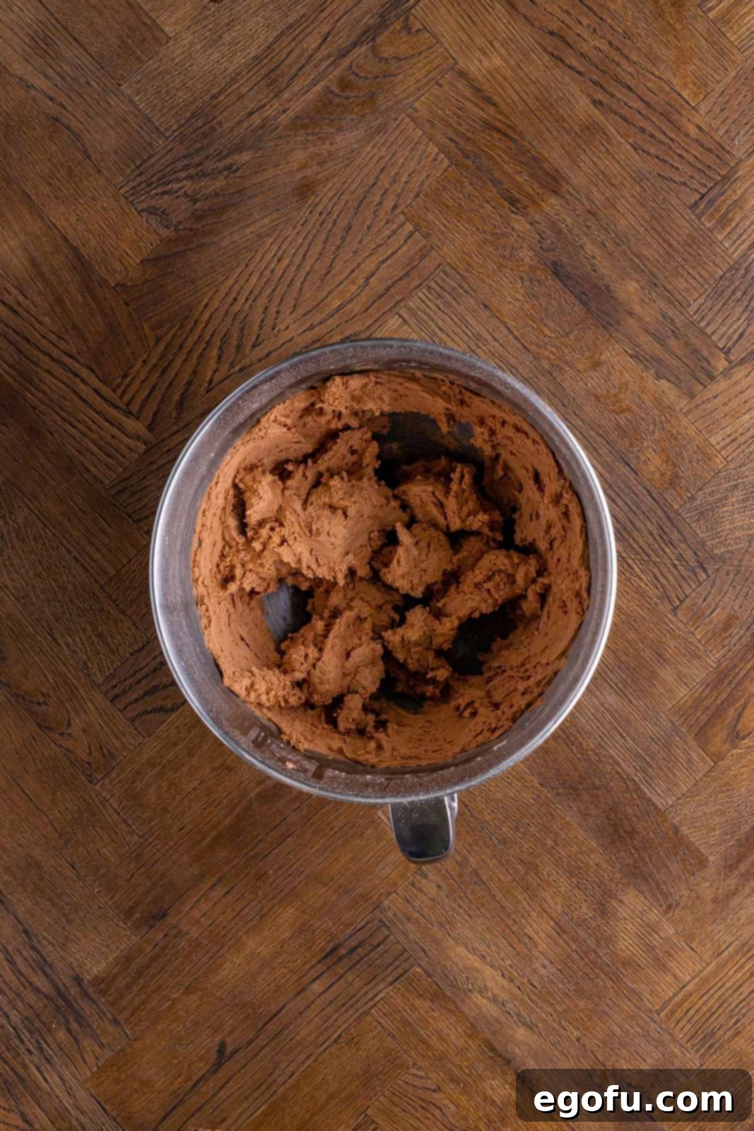A mixing bowl with butter, cocoa powder and powdered sugar mixed together. 