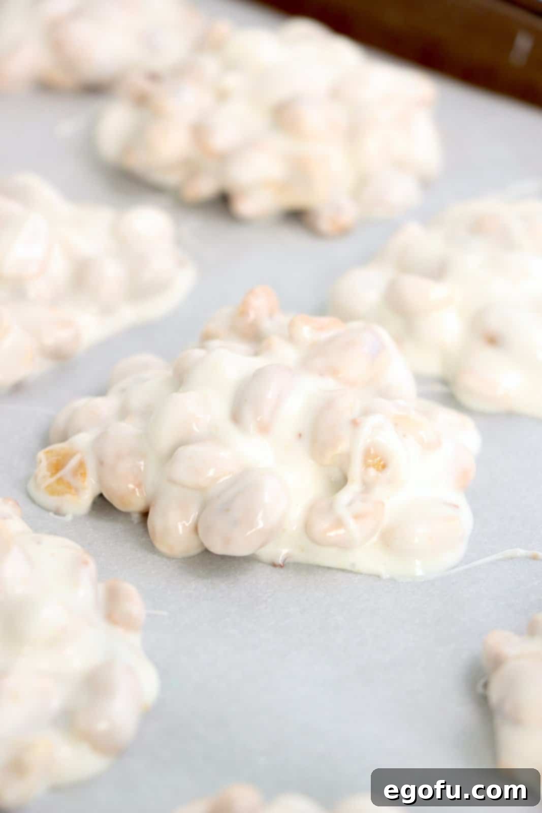 Effortless Slow Cooker Candies 8 Pop candy pieces on a parchment lined baking sheet.