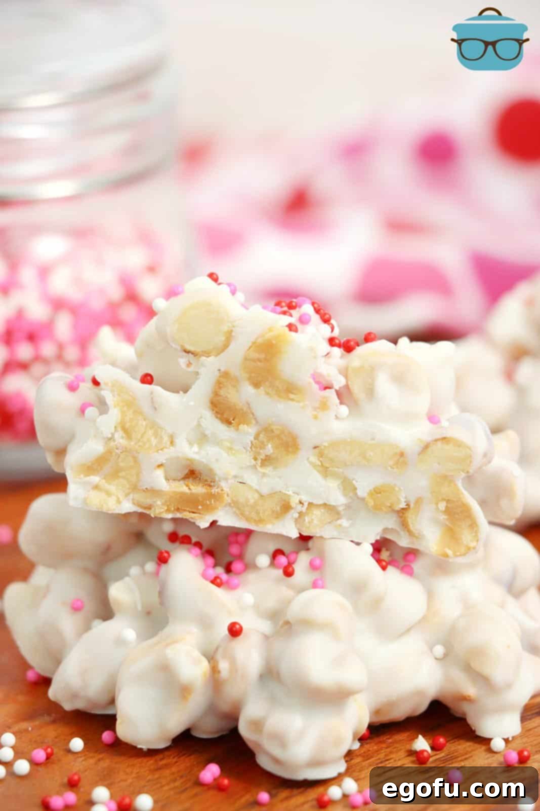 Effortless Slow Cooker Candies 10 A couple pieces of crockpot candy with pink sprinkles on top, one piece broken in half.