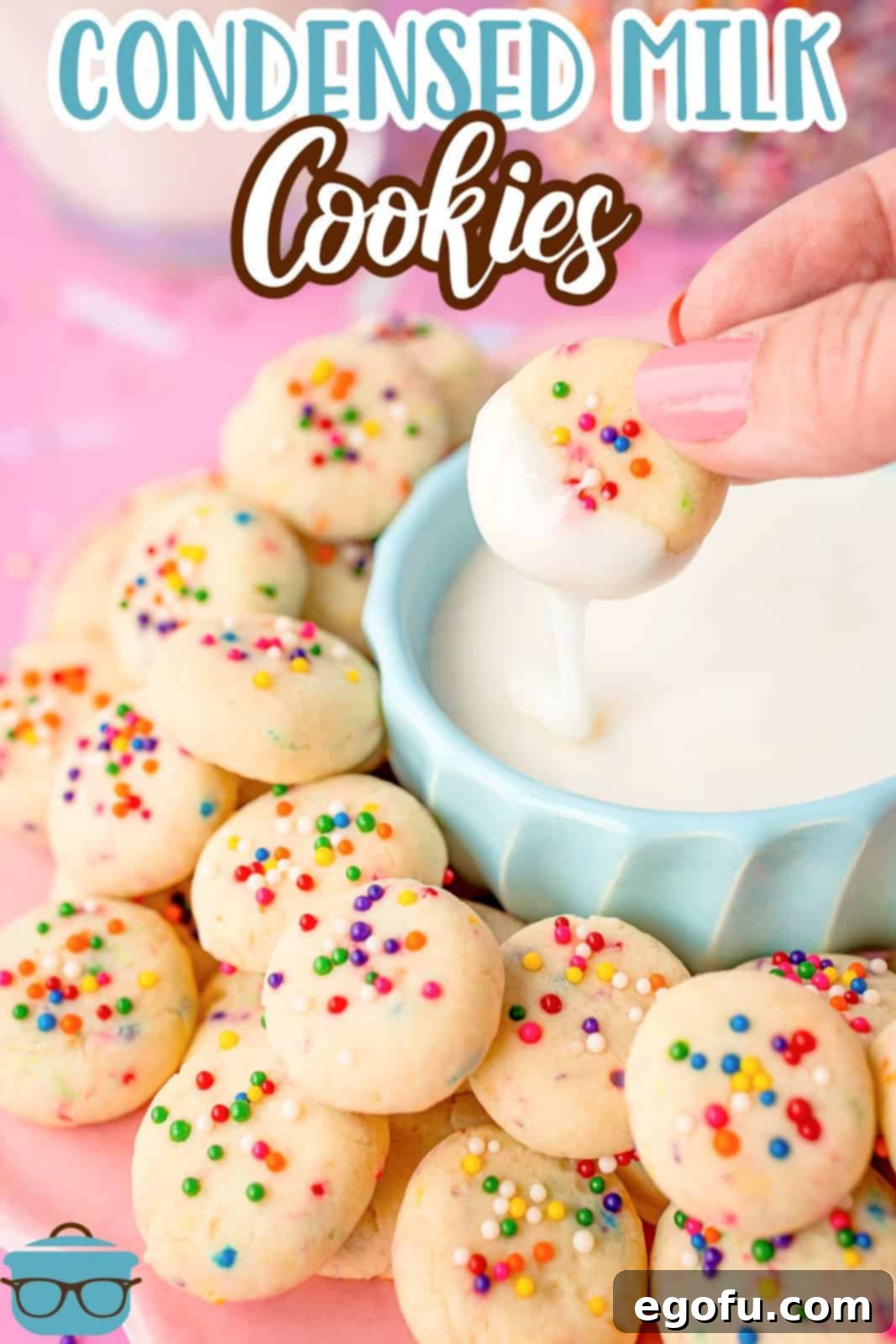 A hand dipping a cookie in a blue bowl of frosting, ready to be enjoyed.