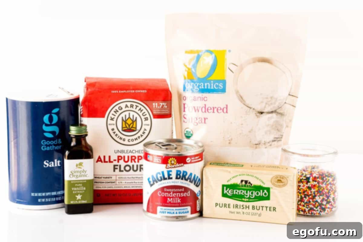 All purpose flour, salted butter, sweetened condensed milk, powdered sugar, vanilla extract, salt, frosting, and rainbow nonpareils laid out, ready for baking.