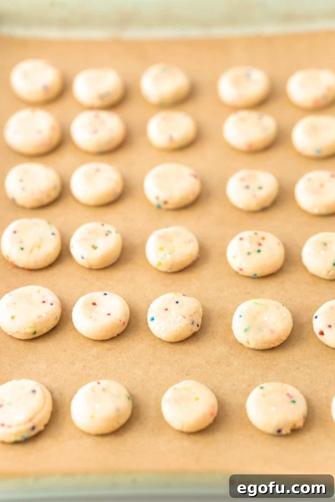 A baking sheet of small pressed cookies, fresh out of the oven, waiting to cool.