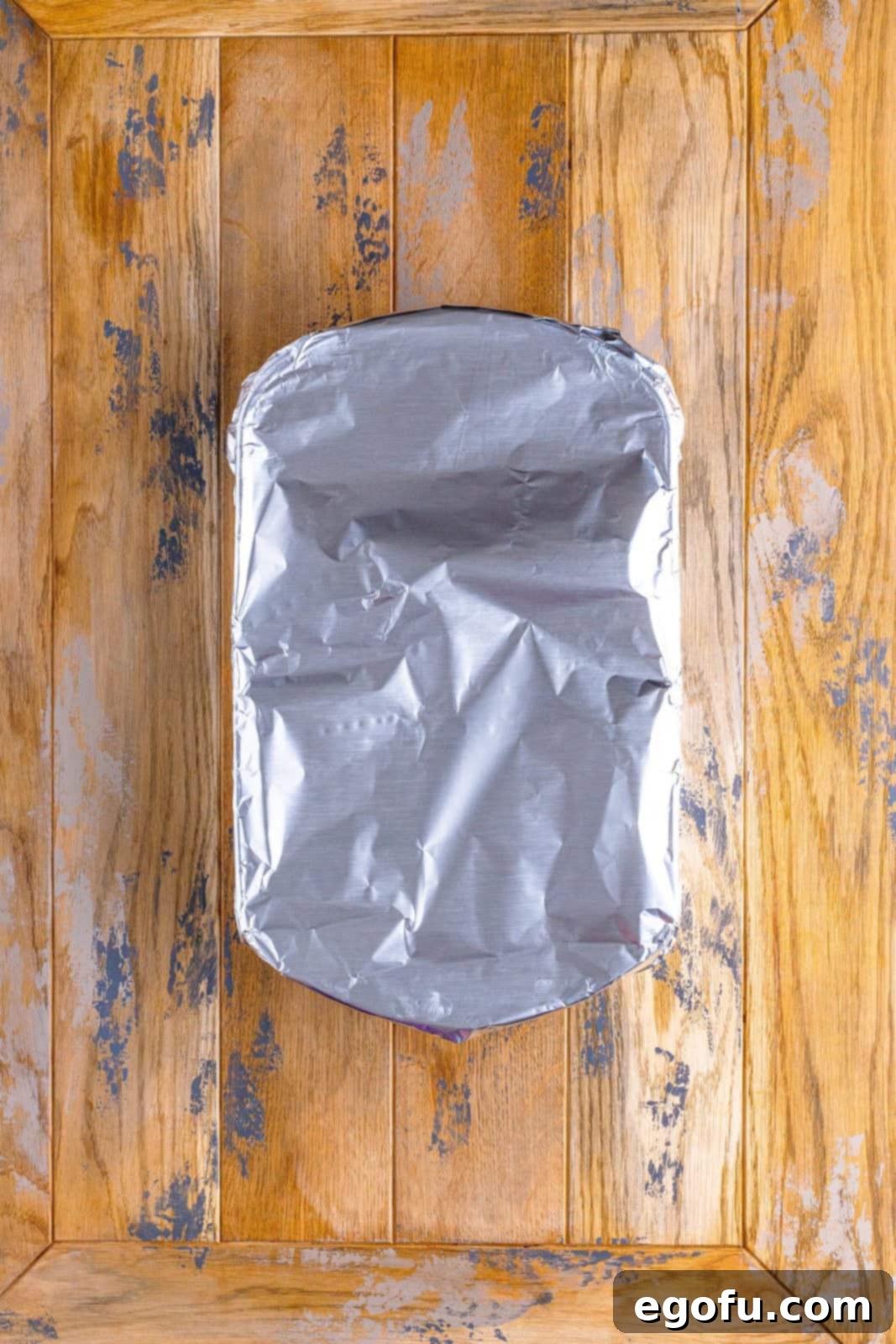 A baking dish, securely covered with aluminum foil, indicating it's ready for its initial baking period in the oven.