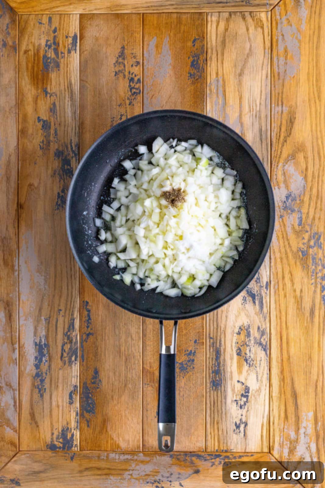 Skillet with onion, pepper, butter, and sugar simmering to caramelize, emitting a delicious aroma.