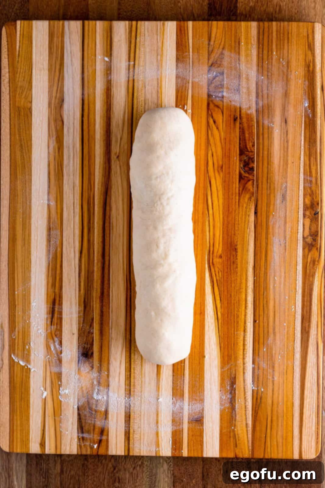 A rolled up uncooked sausage bread, showing the jelly-roll technique.