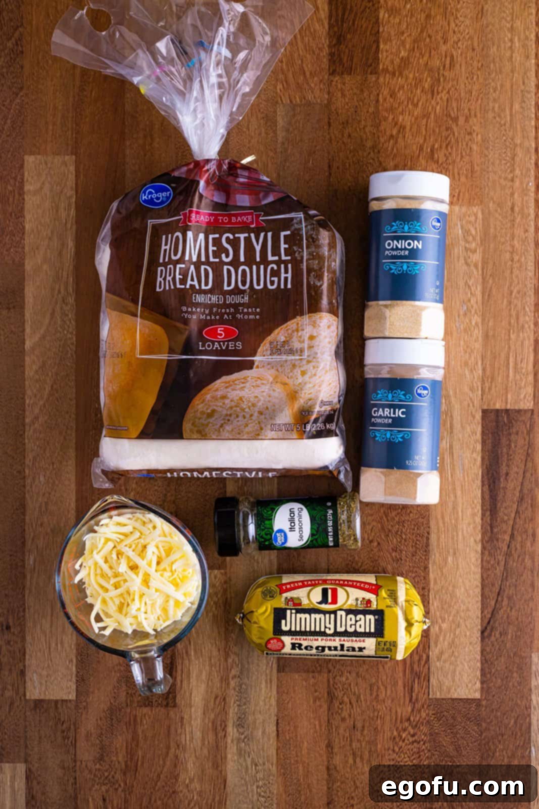 A visual display of all the main ingredients: Breakfast sausage, frozen bread loaves, shredded cheese, Italian seasoning, garlic powder, and onion powder.