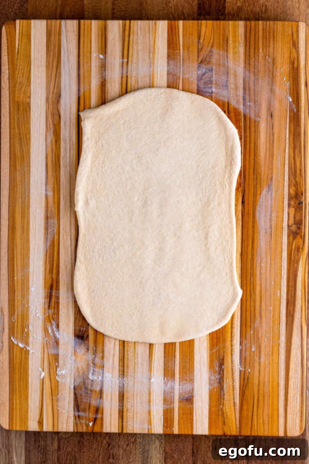 Bread dough evenly flattened out on a counter, ready for filling.