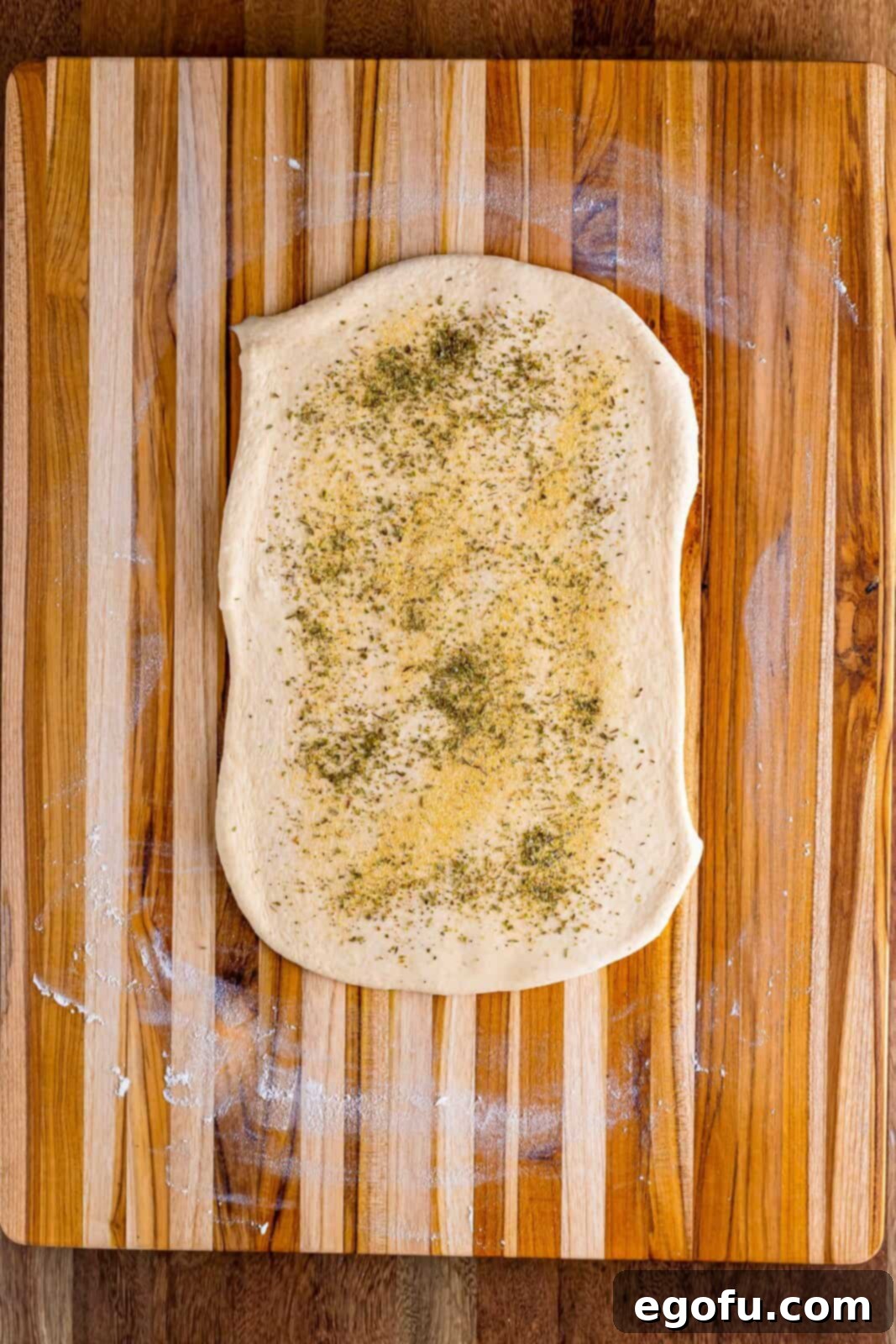 Italian seasoning, garlic powder, and onion powder carefully sprinkled on top of the dough.