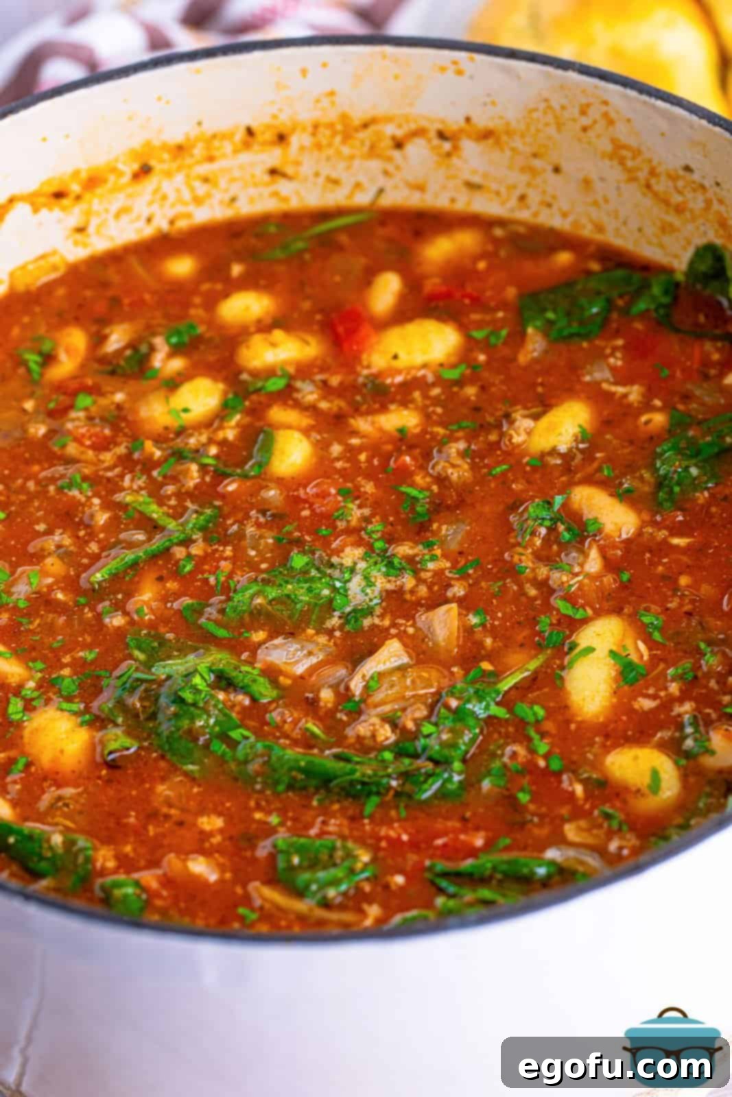 Fresh chopped parsley ready to garnish a pot full of vibrant Italian tomato based Gnocchi Soup.