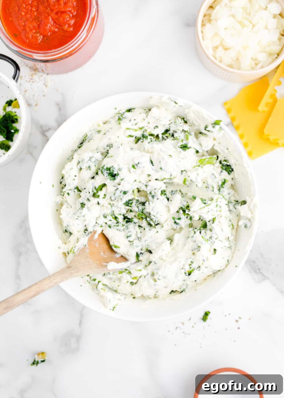 A bowl of creamy ricotta cheese mixed with well-drained spinach, seasoned lightly.