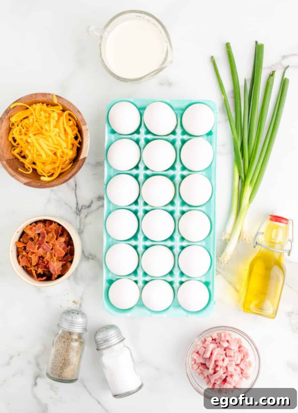 Baked Sheet Pan Eggs 4 A beautiful flat lay photograph showcasing all the fresh ingredients needed for Sheet Pan Eggs: raw eggs, vibrant green scallions, shredded cheddar cheese, cooked bacon, diced ham, salt, pepper, olive oil, and a small jug of heavy cream, arranged on a rustic wooden surface.