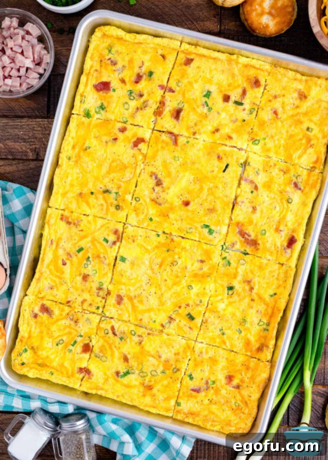 Baked Sheet Pan Eggs 8 A perfectly baked sheet of eggs, golden brown and bubbling with toppings, cooling on the baking pan after being removed from the oven, ready to be portioned.
