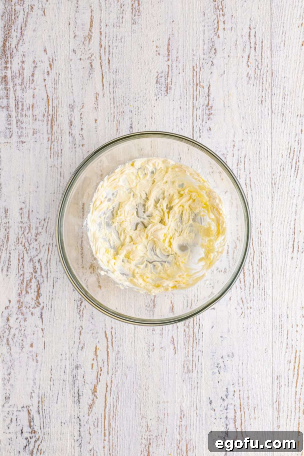 A mixing bowl containing smoothly whipped cream cheese, ready for the next ingredient.