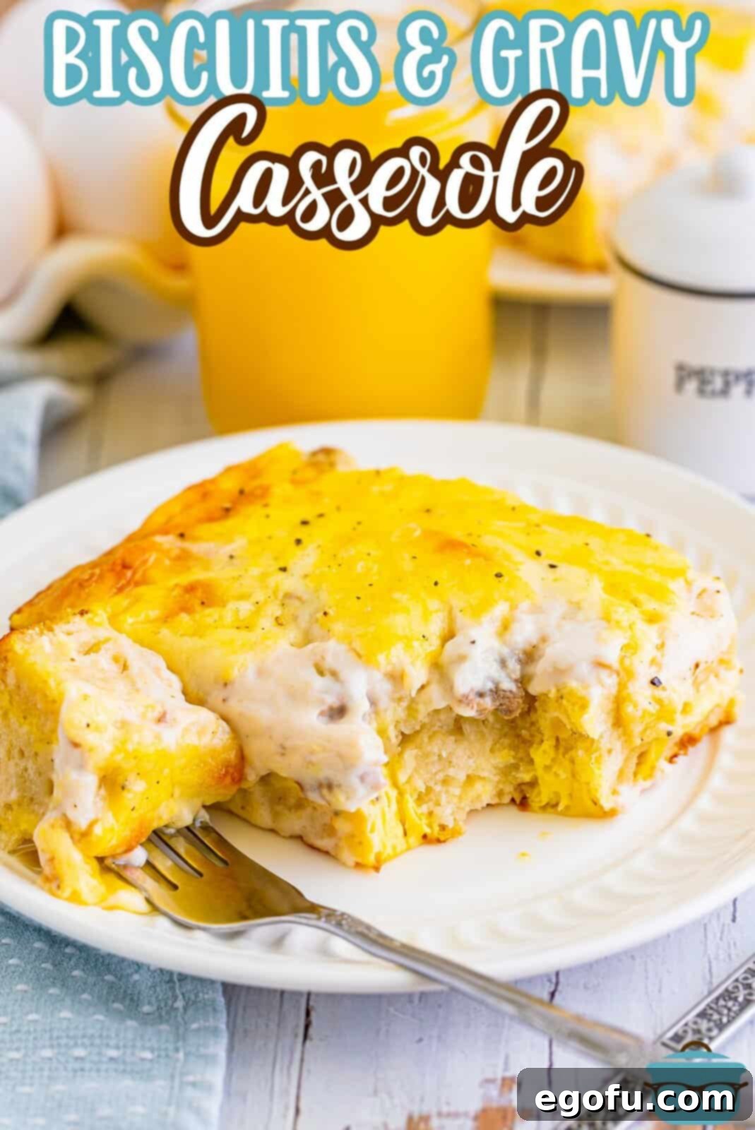 A fork taking a bite from a serving of Biscuits and Gravy casserole, showing the fluffy biscuit and creamy gravy.