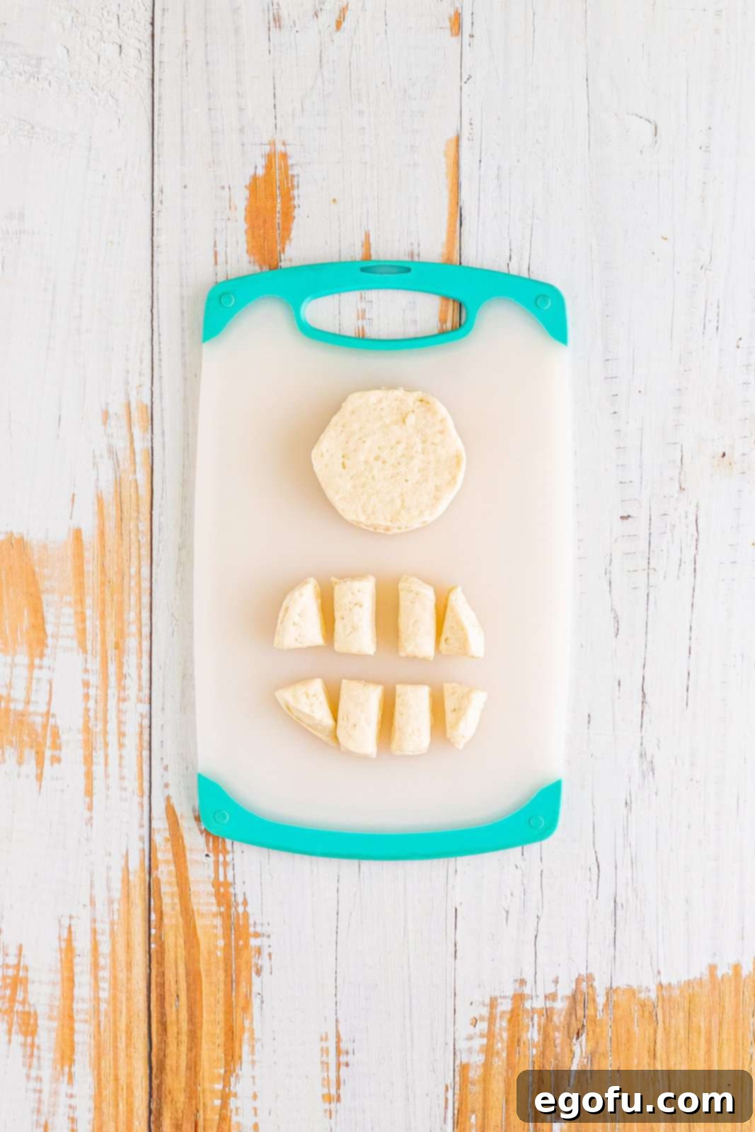 Biscuits on a cutting board, one whole and one cut up into eight pieces.