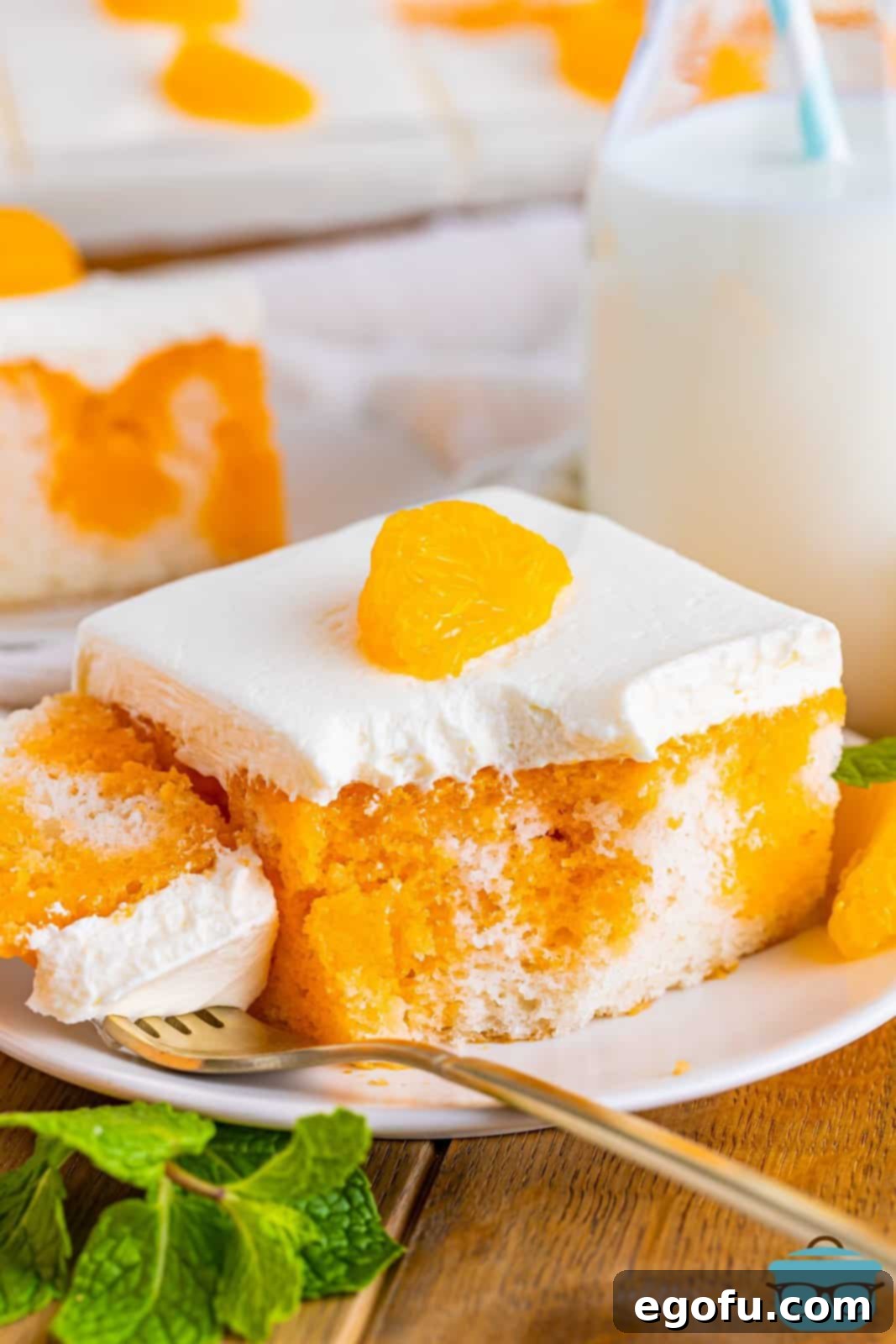 A slice of Orange Creamsicle Poke Cake with a forkful taken out.