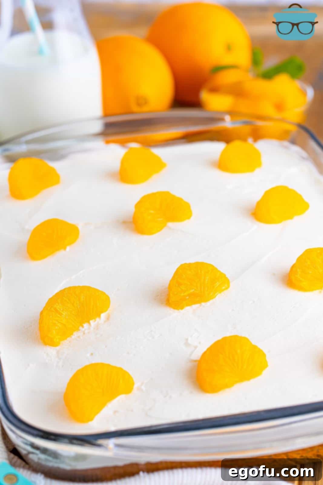 A baking dish with Orange Creamsicle Poke Cake with mandarin oranges on top.